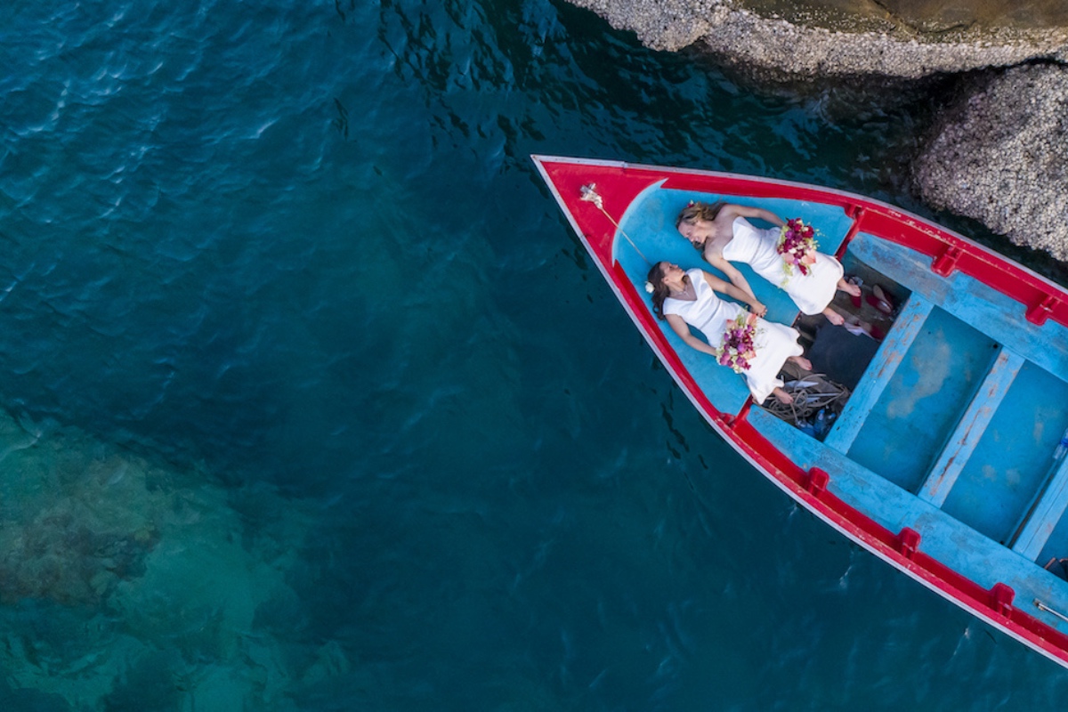 Drone photo looking down into an open boat with Jessica and Alicia lying down side by side on their wedding day at Koh Tao, Thailand.