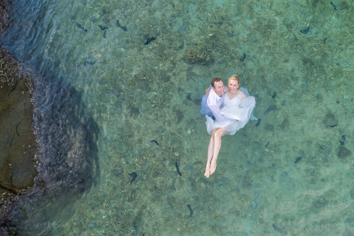 A drone photo looking down on Maaike and Nahum in the water in their wedding finery on their elopement wedding day on Koh Tao.